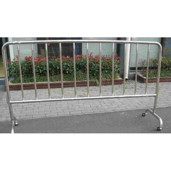 A crowd control barrier with bridge feet and four wheels stands on the concrete.